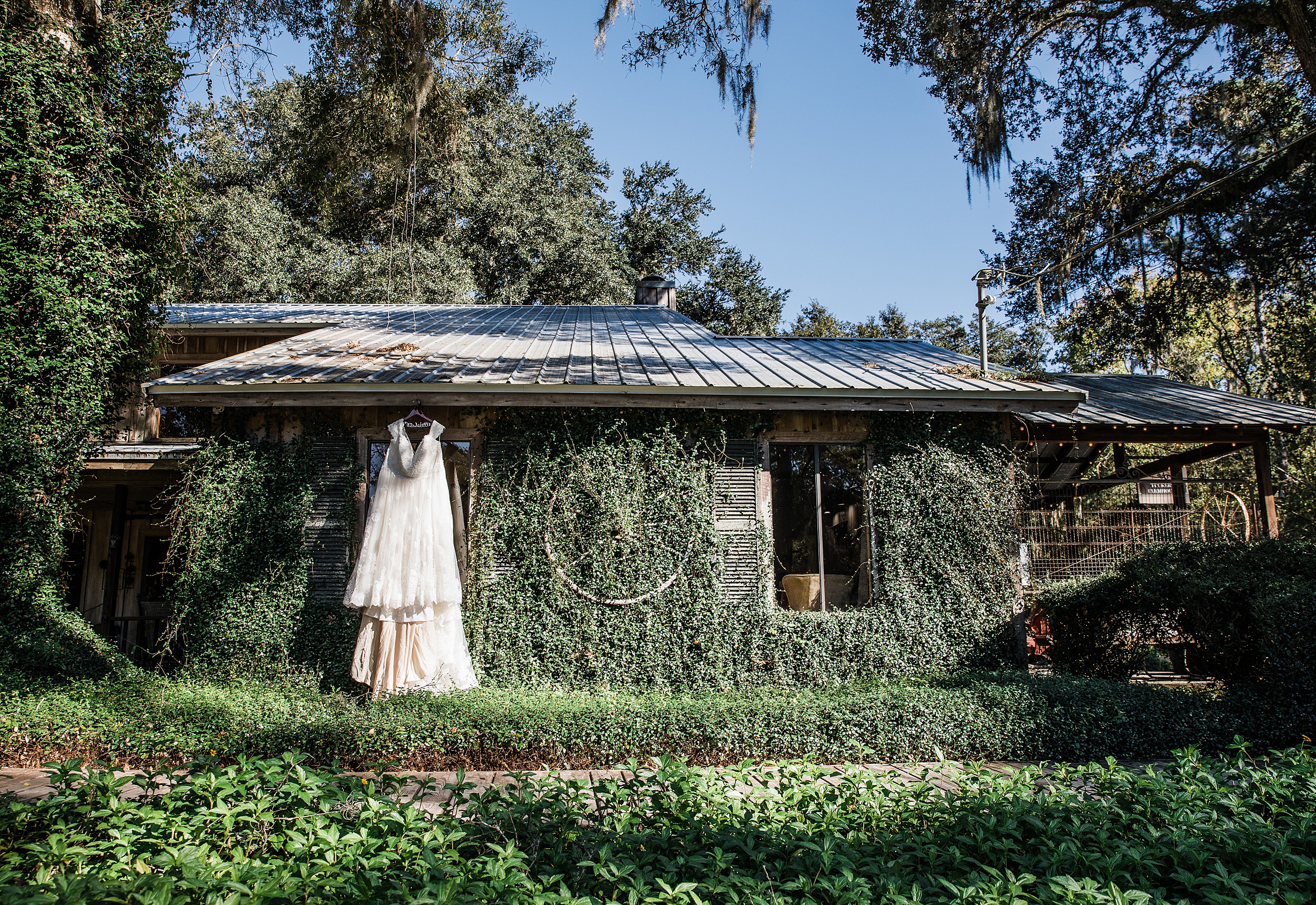 A wedding dress hangs on the vine covered bridal suite a tucker's farmhouse wedding venue
