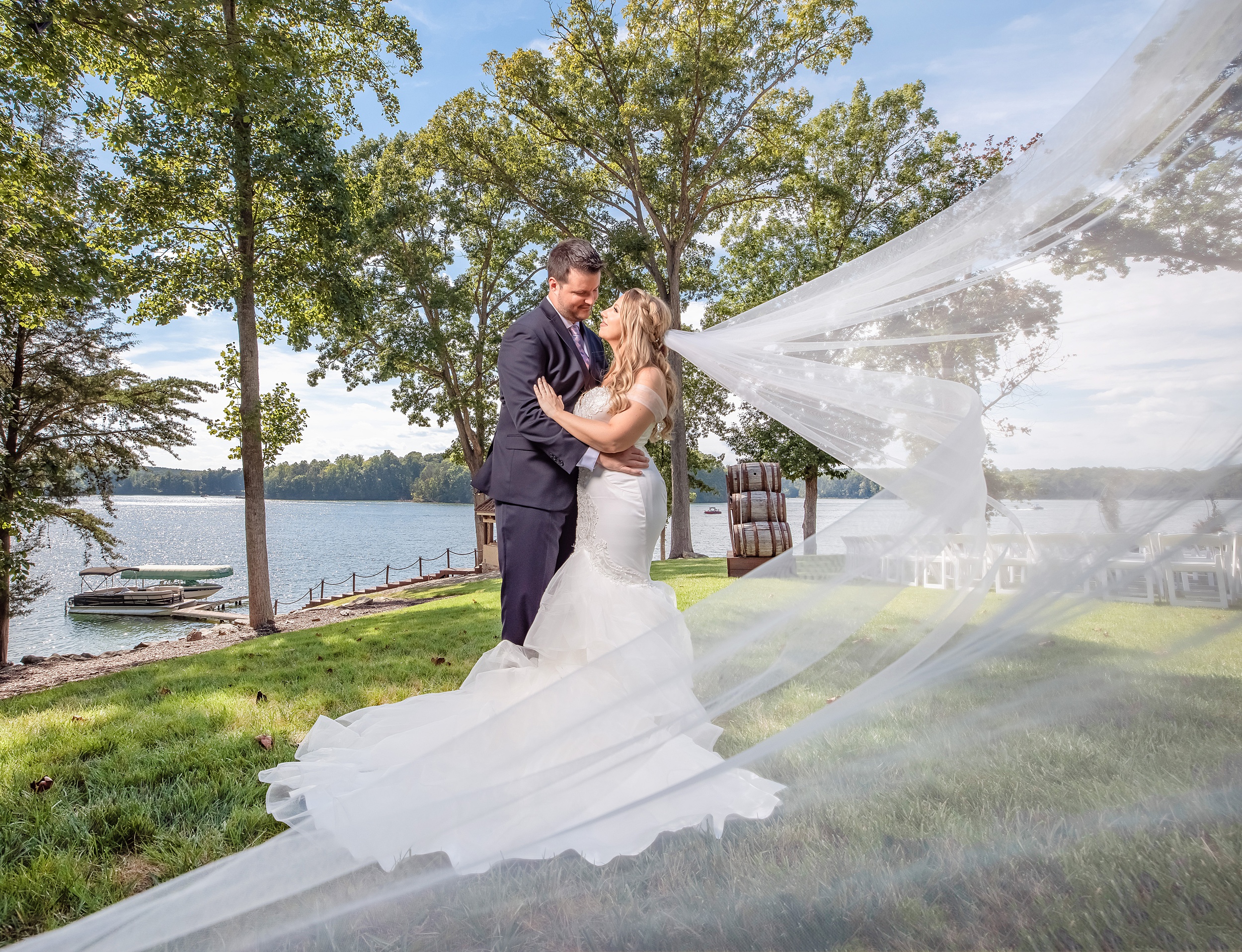 Newlyweds share an intimate waterfront moment as the veil flows in the wind around them