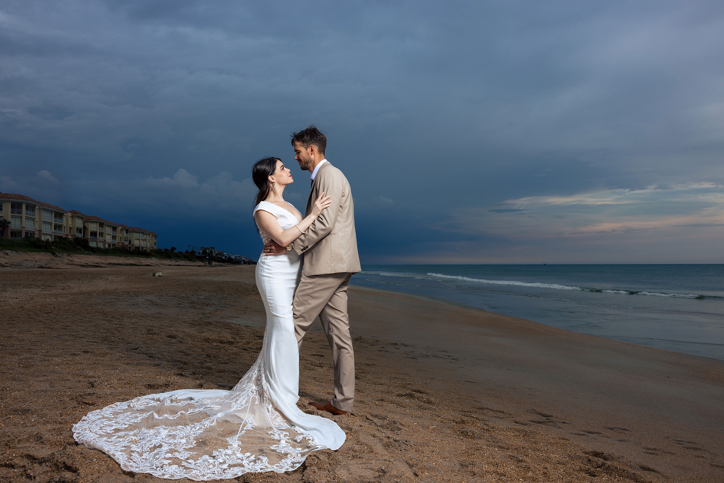 Newlyweds stand on the beach staring into each other's eyes at sunset