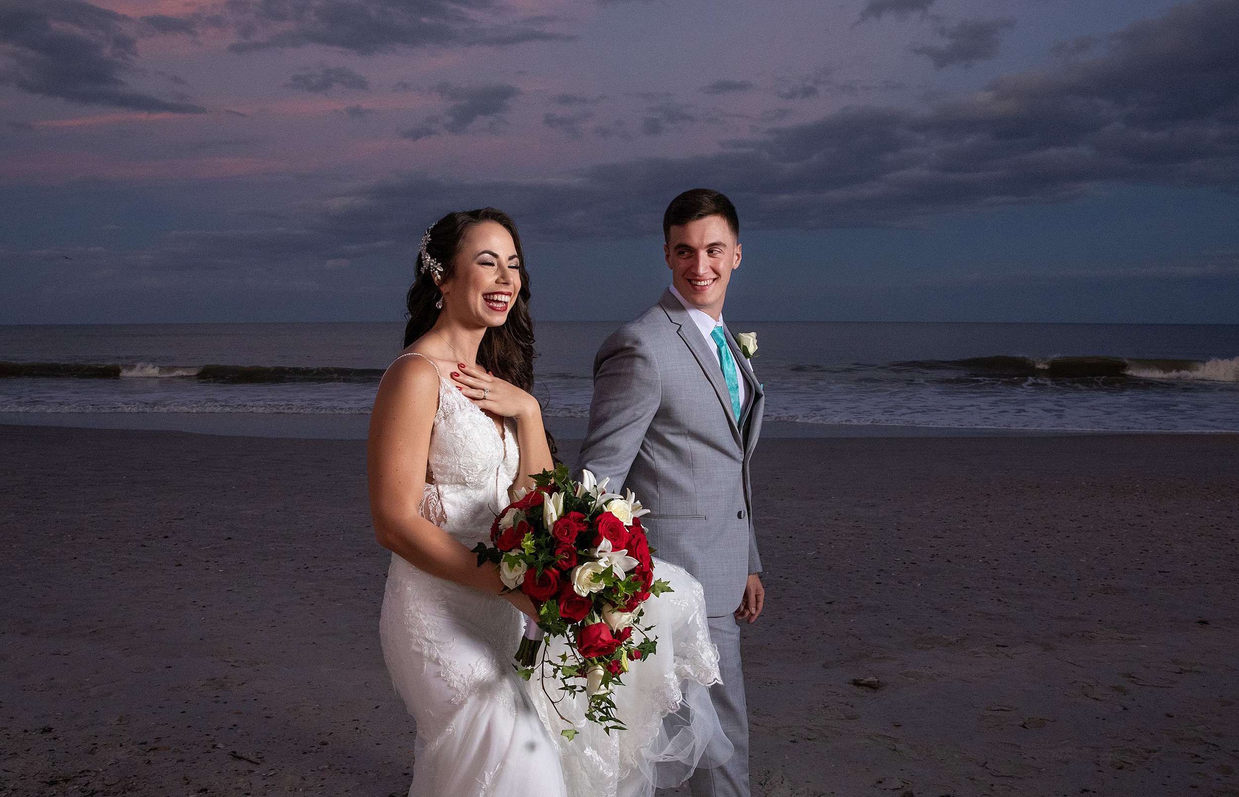 A bride laughs while walking down the beach at sunset with her groom at their the lodge and club ponte verda wedding