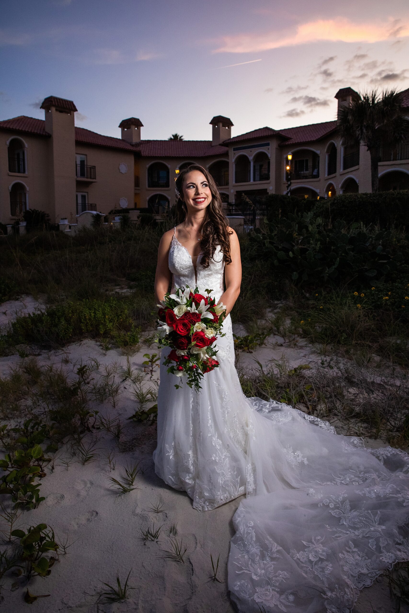 A bride smiles big while standing on the beach at sunset behind the lodge and club ponte verda wedding venue