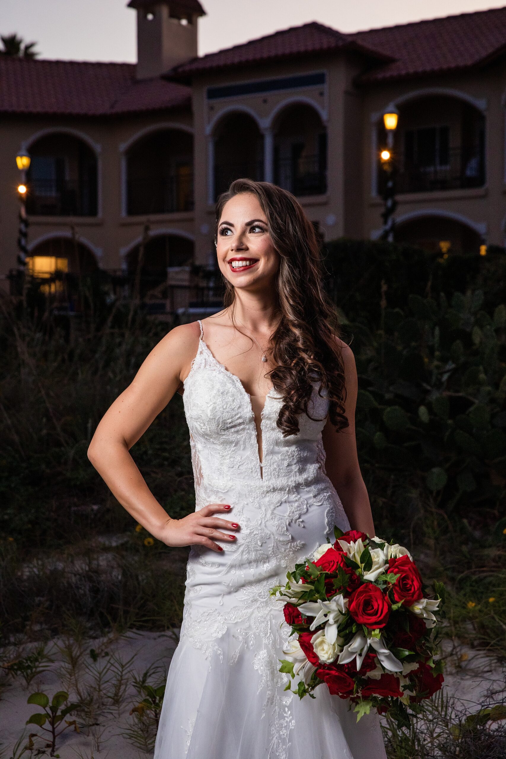A bride stands in her embroidered dress holding her red bouquet at the lodge and club ponte verda wedding venue