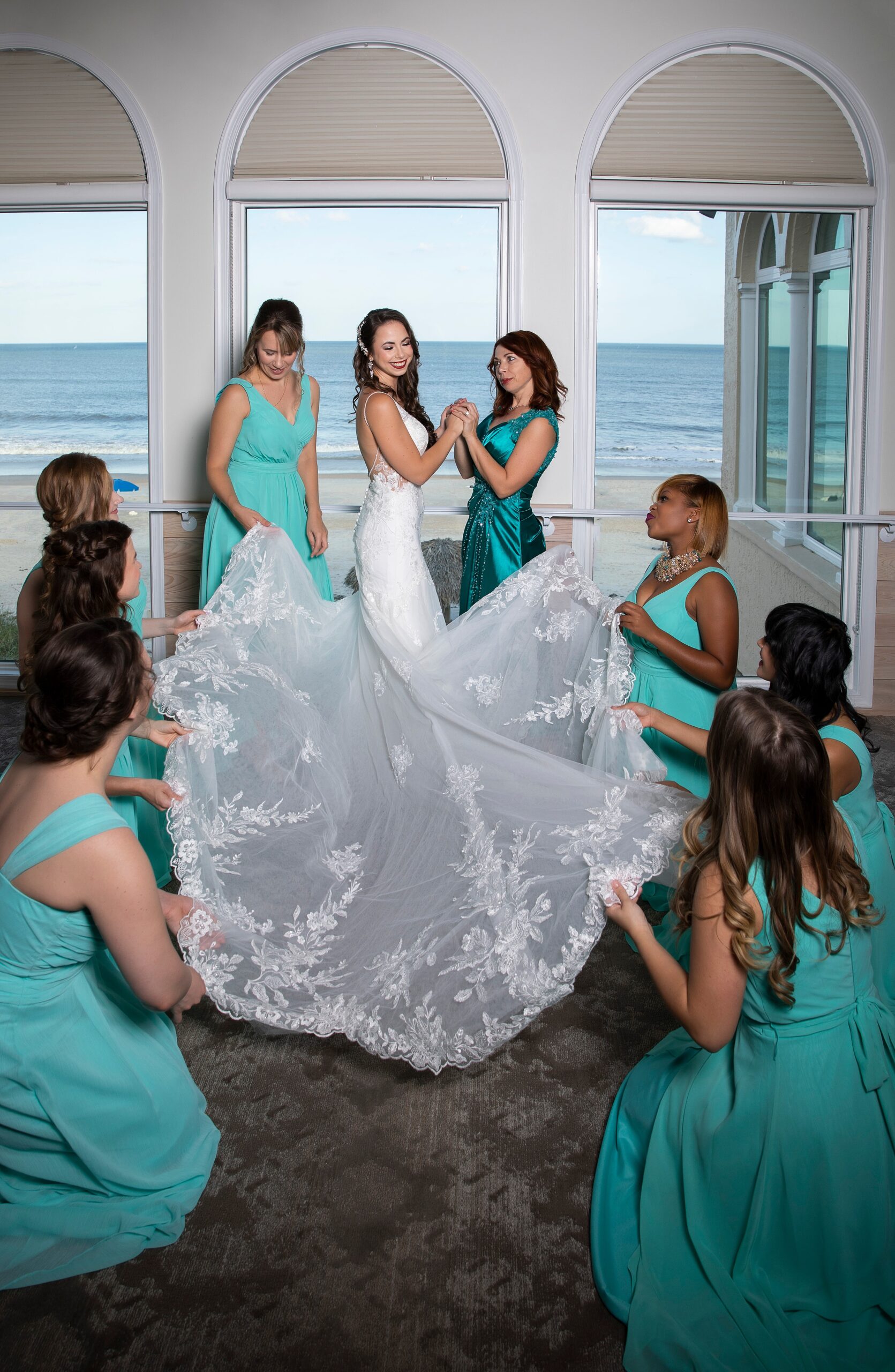 A bride shows off her beautiful dress to her bridesmaids in a beachfront suite