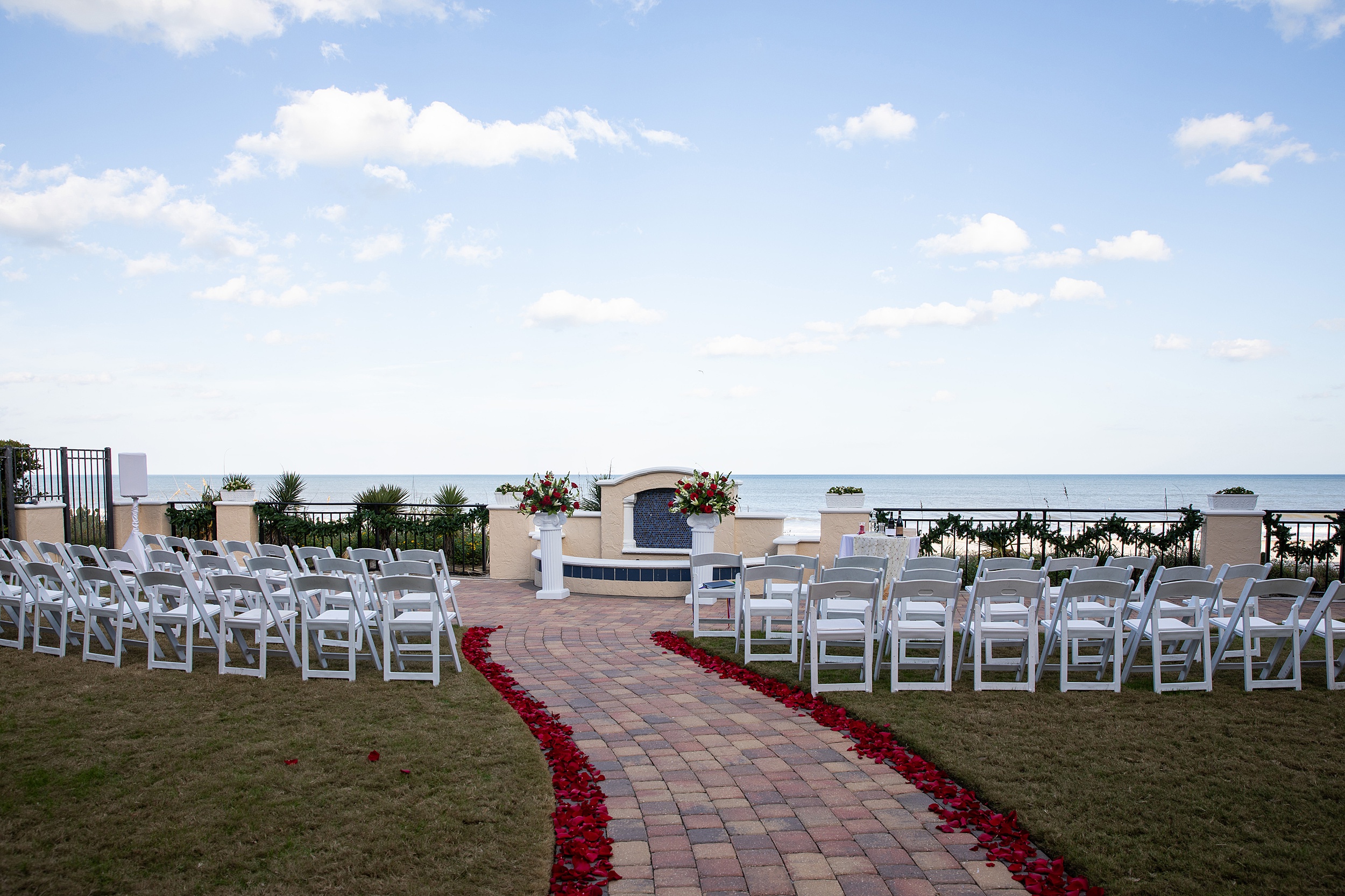 Details of a the lodge and club ponte verda wedding ceremony set up with white chairs and red floral petals