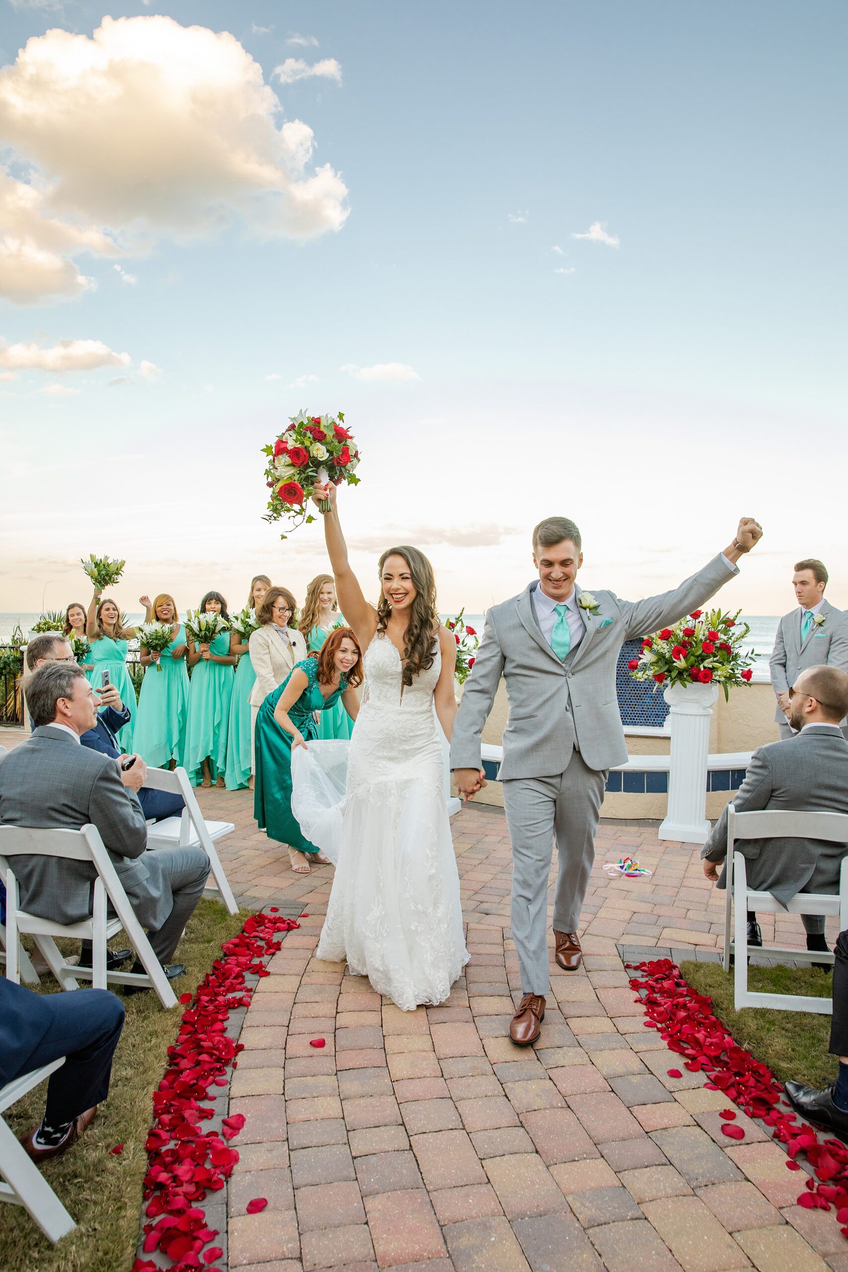 Newlyweds celebrate while exiting the rose petal lined the lodge and club ponte verda wedding ceremony overlooking the beach