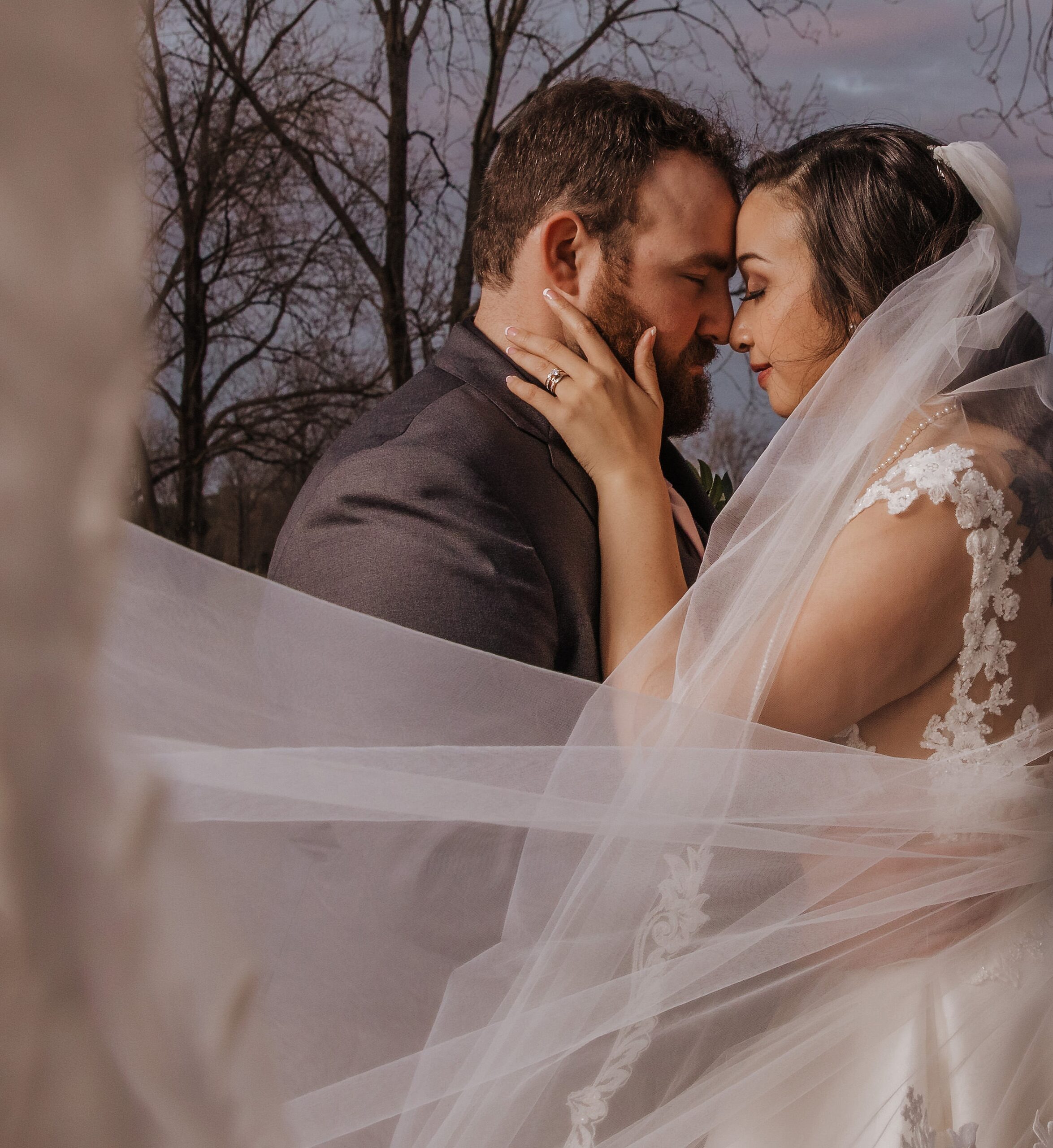 Newlyweds share an intimate moment touching foreheads in the woods at their the manor at 12 oaks farm wedding
