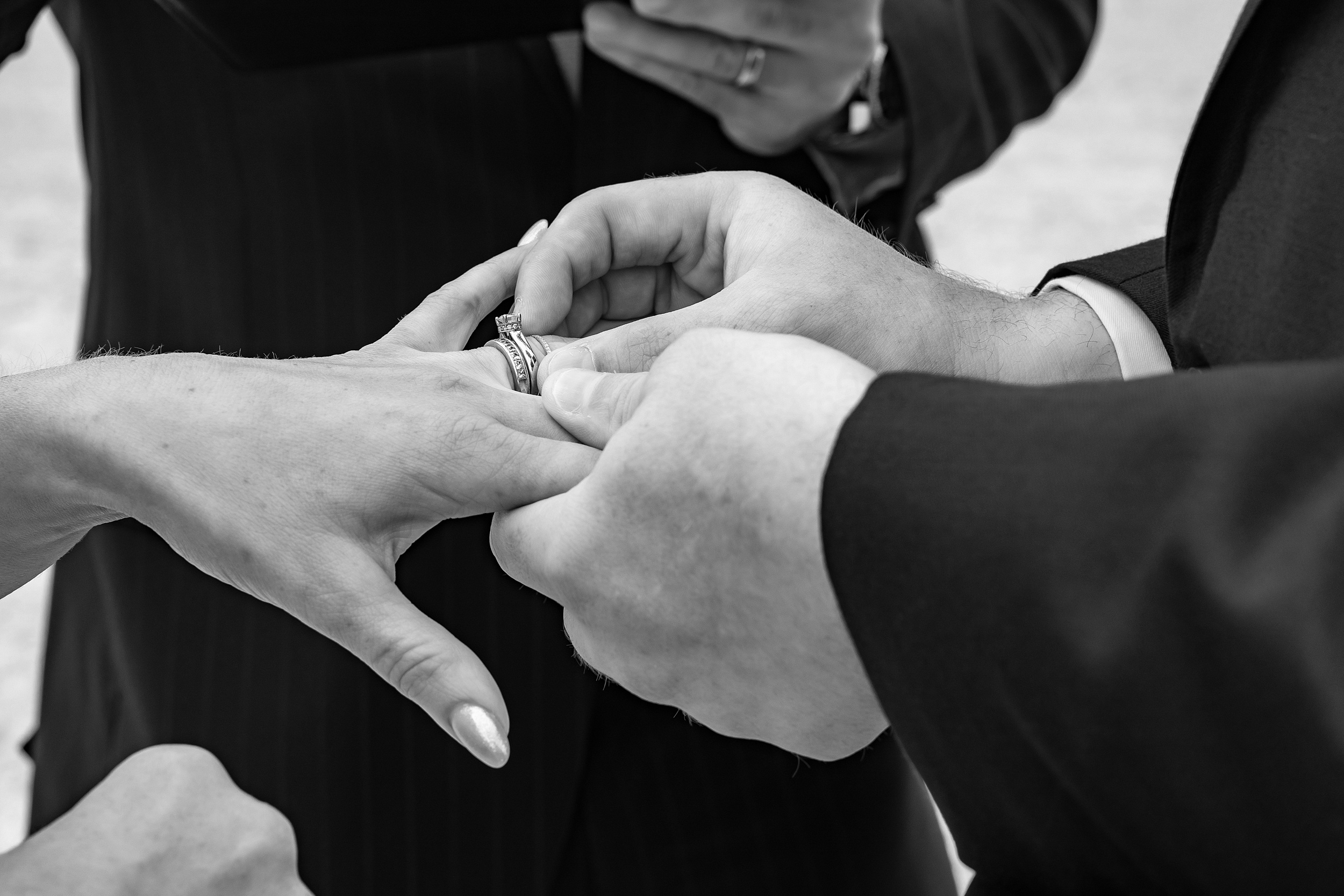 Details of a groom putting the ring on his bride's finger during their Sterling Event Venue wedding ceremony