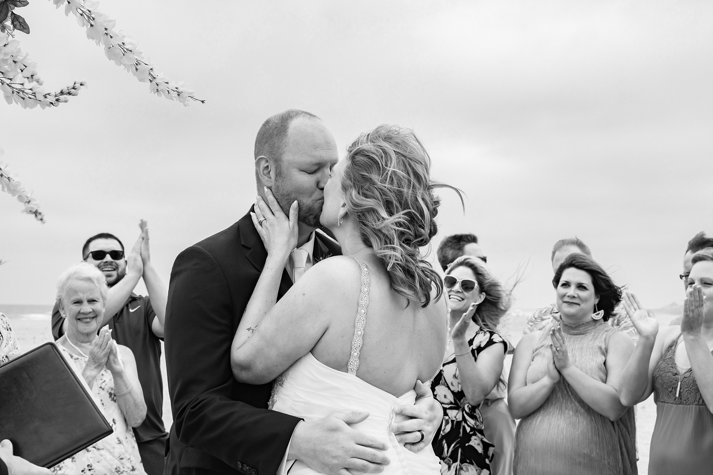 Newlyweds kiss on a beach before their Sterling Event Venue wedding reception