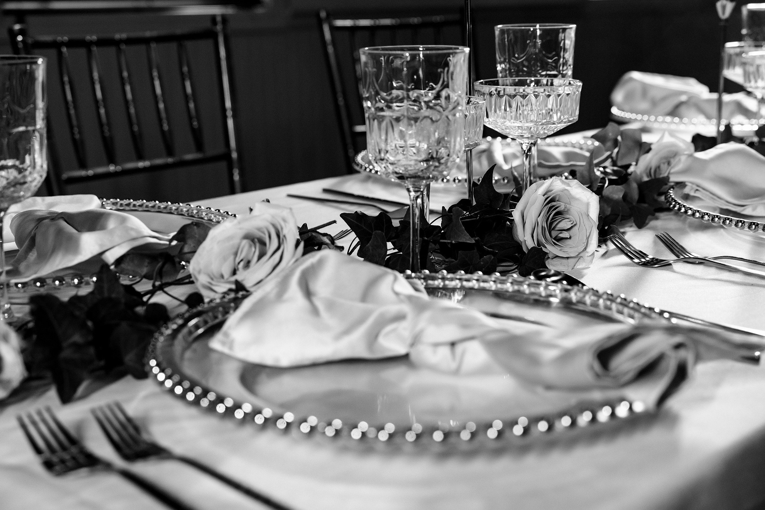 Details of a wedding reception table setting with crystal glasses and roses