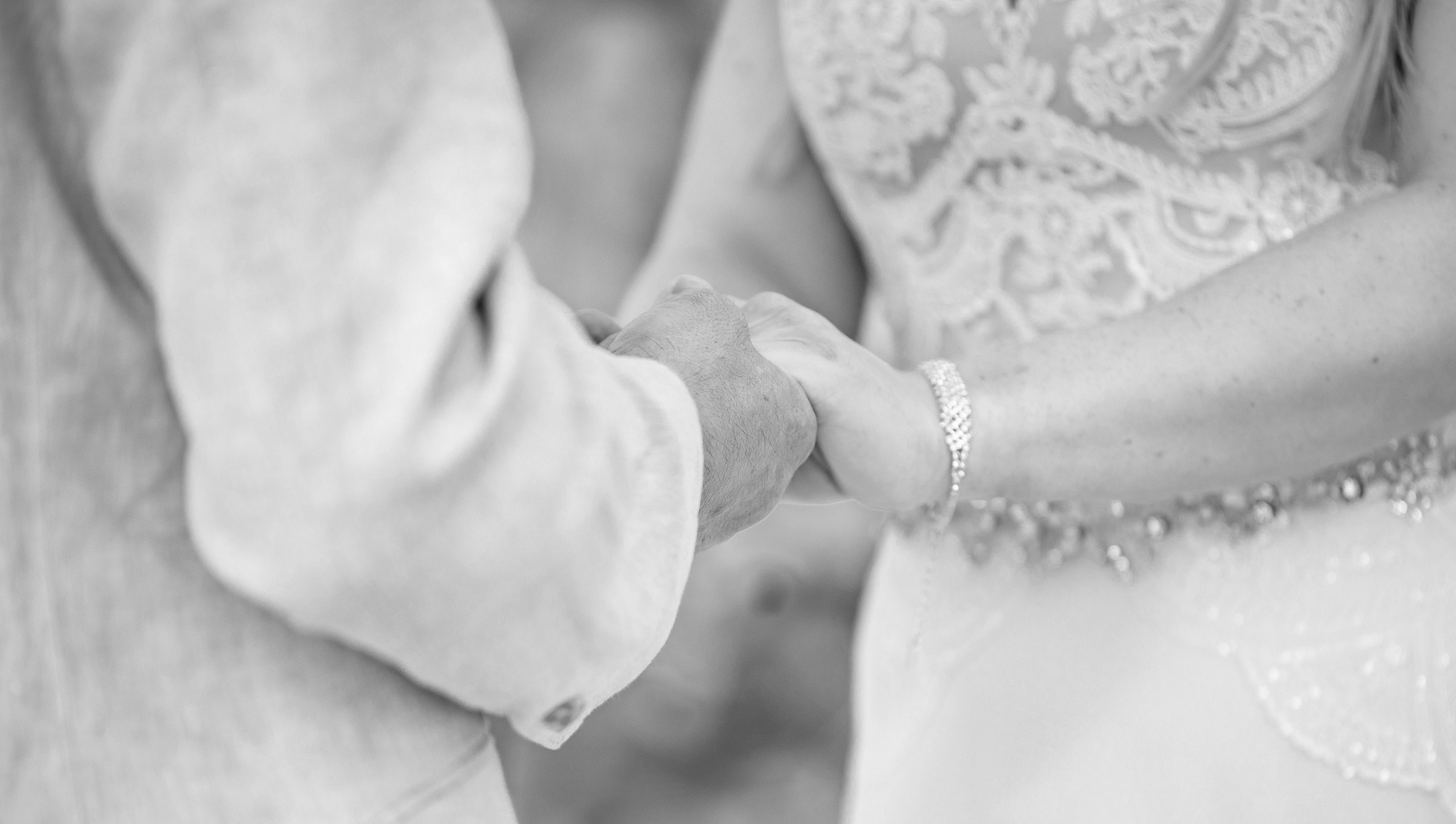 Newlyweds hold hands while standing in a garden